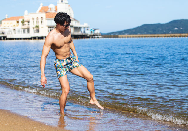 恐る恐る水に足を入れるマッチョ2｜海辺で脚の筋肉が見える男性のフリー写真｜muscular man putting his foot in the water, leg muscles beach stock photo